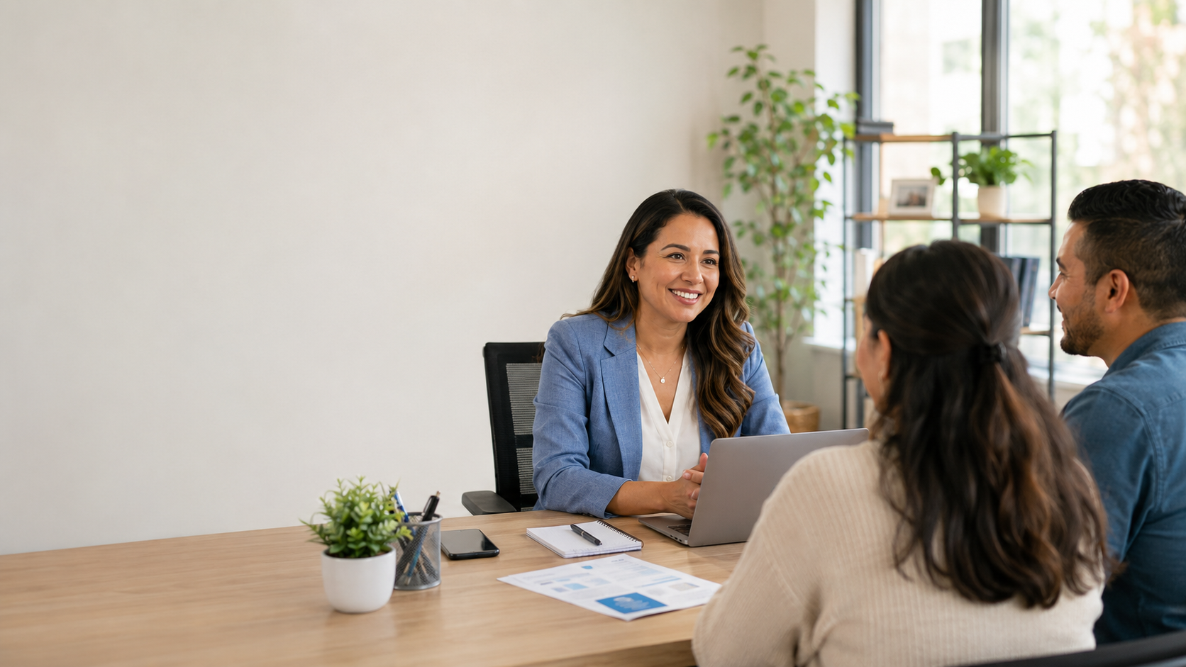 Asesora financiera bilingüe latina recibiendo a una pareja para consulta inicial
